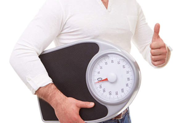 减肥后举起秤竖起大拇指的男人。