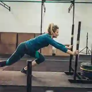 Woman pushing a weighted sled in the gym.