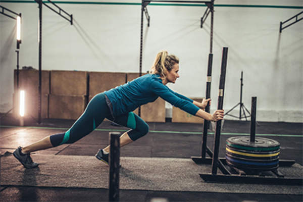 一个女人在健身房推着一个加重的雪橇。