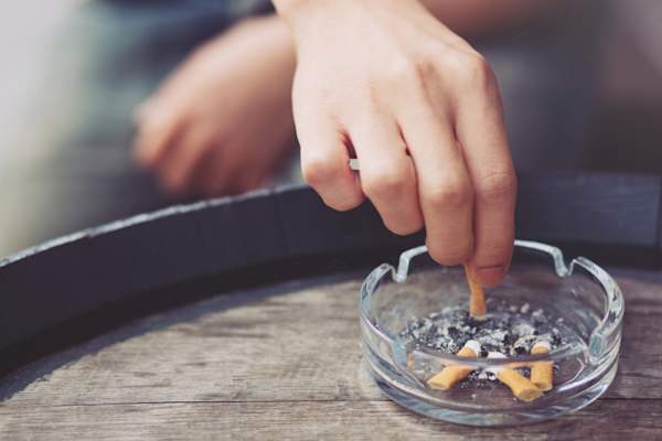 手在烟灰缸里熄灭香烟