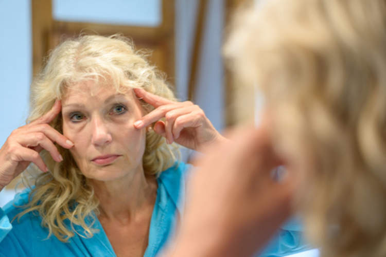 女性在镜伸展远离皱纹。