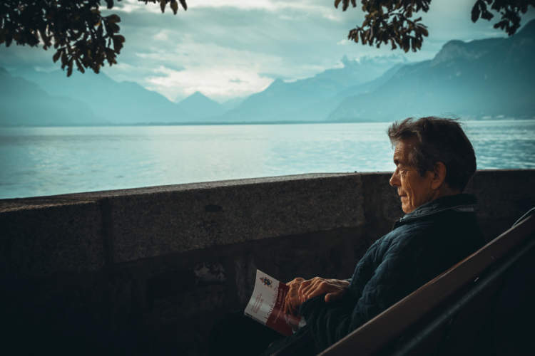 坐在湖边拿着书的老人