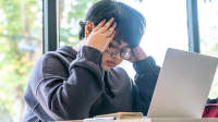 超重的年轻女性，头痛，使用笔记本电脑工作。