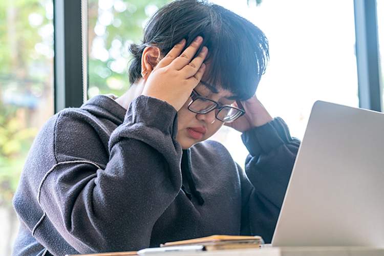 超重的年轻妇女,头痛,在笔记本电脑上工作。