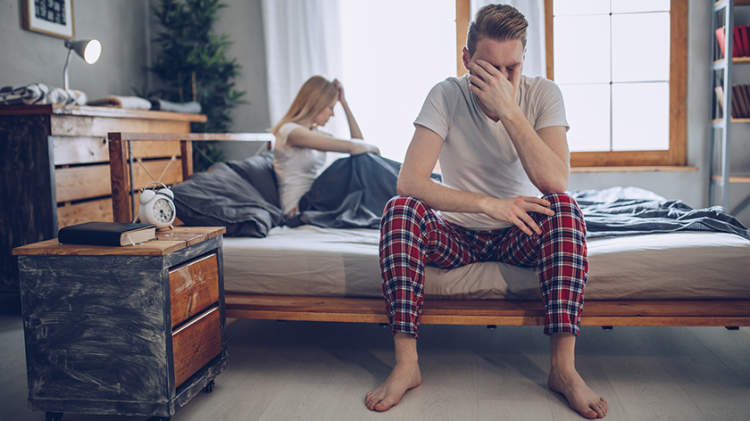 焦虑的男子在床上强调勃起功能障碍。