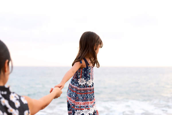 母亲和女儿牵着手，走向大洋的女儿散步