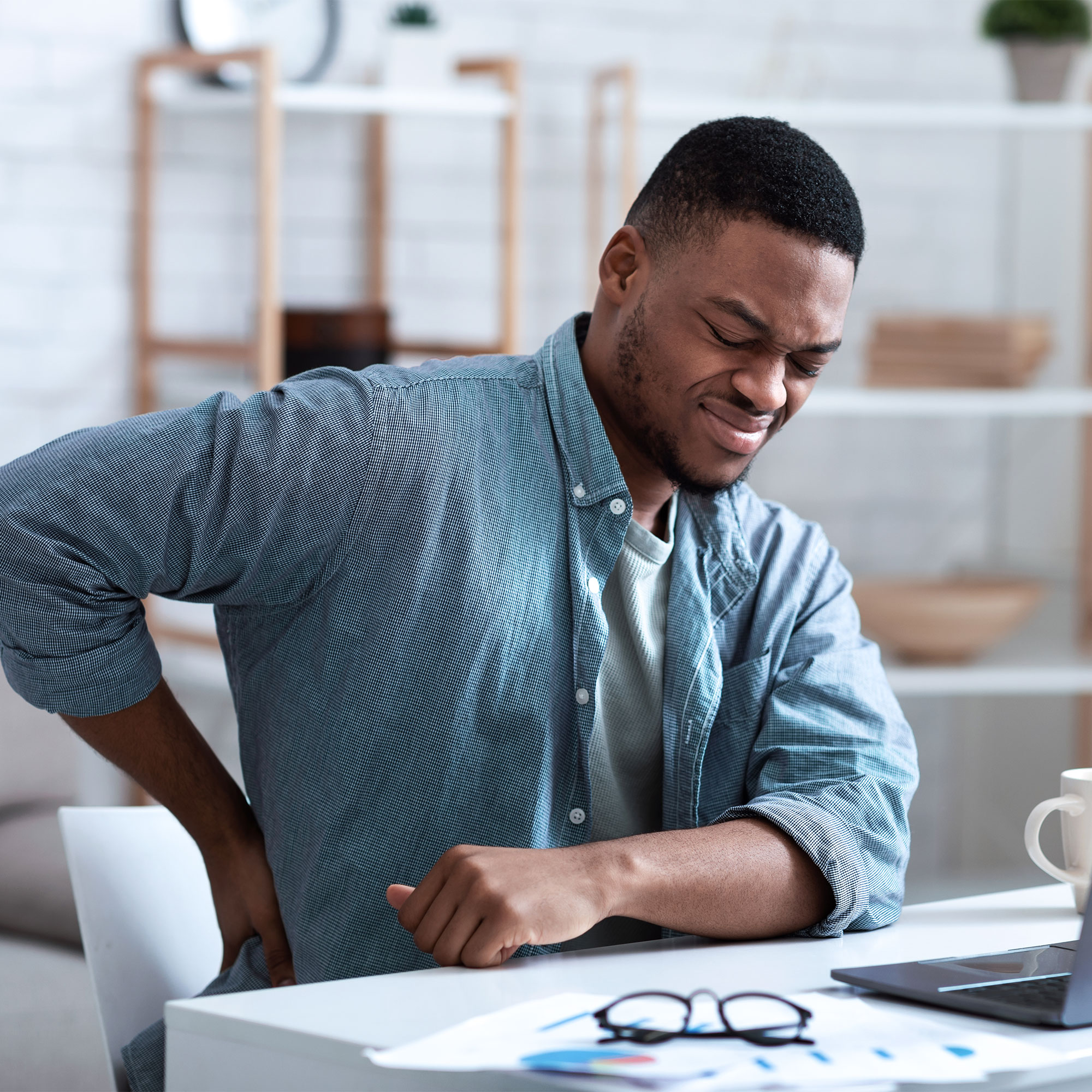 A man touches his lower back in pain
