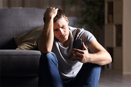 忧心忡忡的年轻人在智能手机上查看社交媒体。
