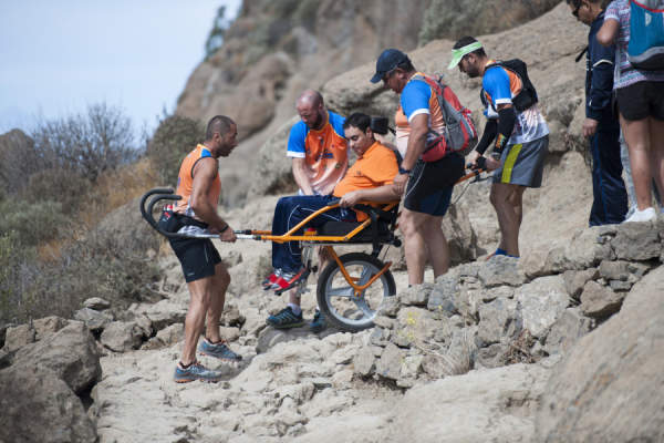 在del Nublo公园的山区，一群人在帮助一个坐在专用移动轮椅上的人。