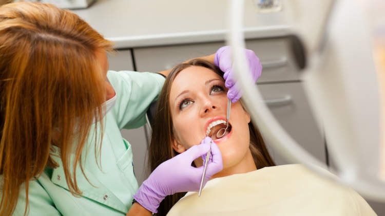 Woman having teeth cleaned at dentist.