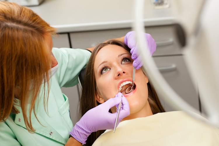 Woman having teeth cleaned at dentist.