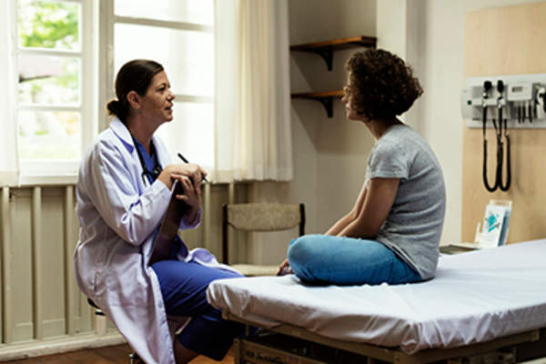 医生在检查室和十几岁的女孩谈话。