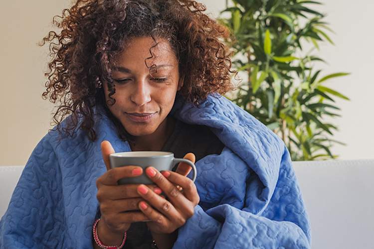 与流感喝茶女人和盖上毯子。