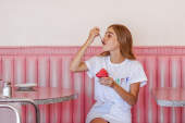 一个坐在粉色座位上吃果子露的女人