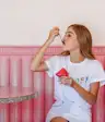 woman eating sherbet while sitting on pink seat