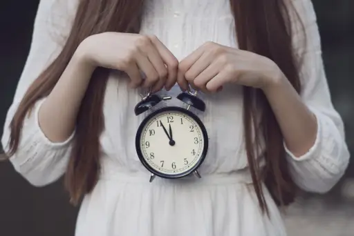 一个女人，她的头不在镜框里，手里拿着一个小的圆形时钟