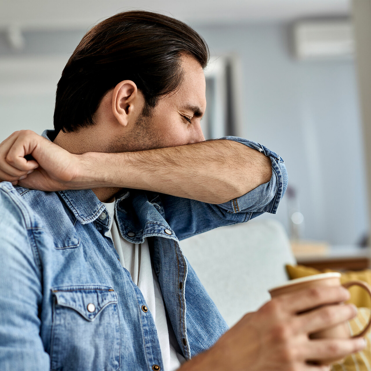 一个男人对着肘部咳嗽