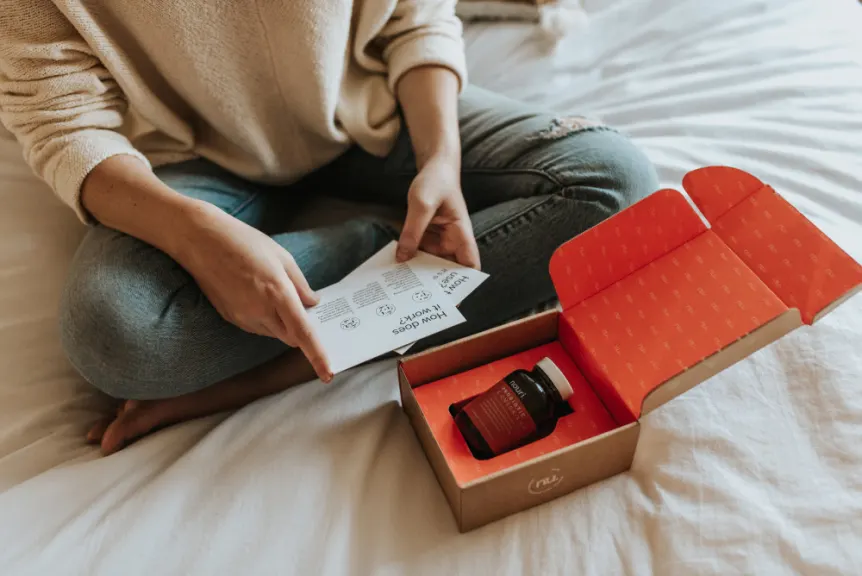 女人坐在床上，阅读包装材料包括在一个补充订阅箱