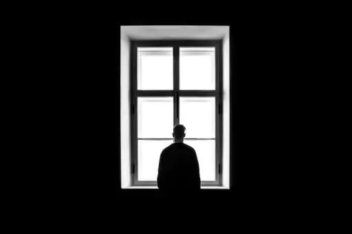 silhouette of man alone staring out window