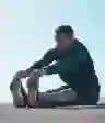 一个年轻人独自坐着伸展他的腿筋