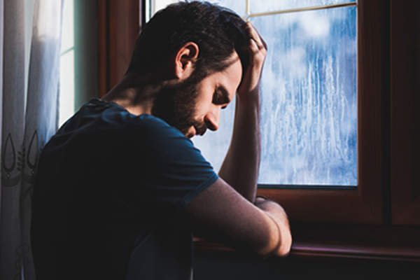 一个悲伤的年轻人,手放在前额上。