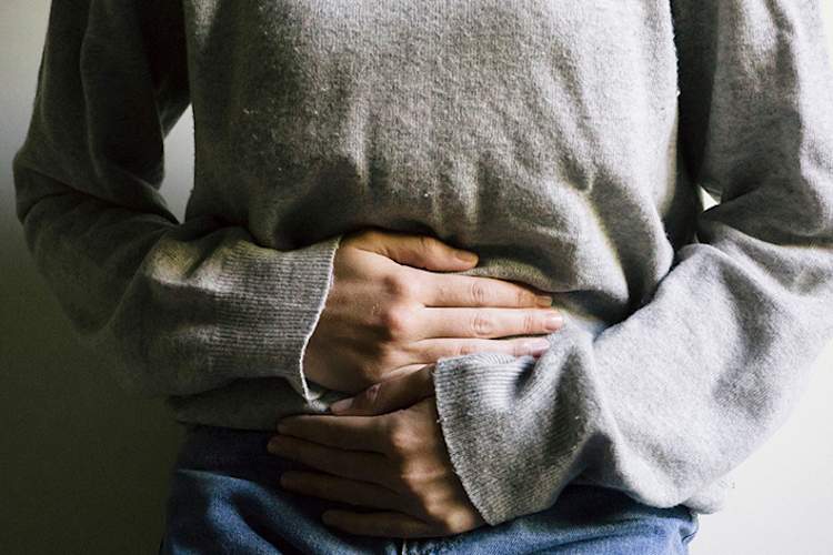 女人痛得撑着肚子。