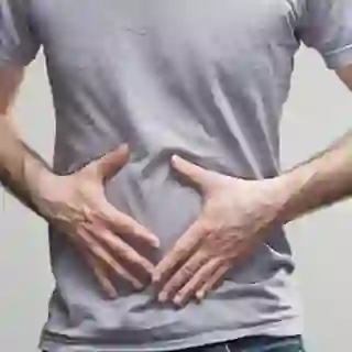 Man with digestive problems, hands on stomach.