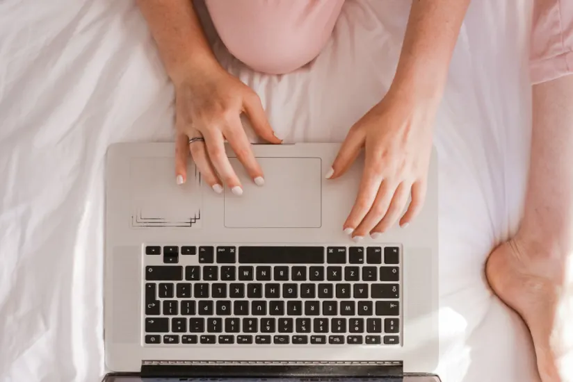 穿着粉色裤子的女人在笔记本电脑上打字