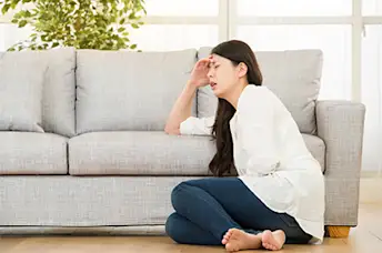 有胃痛的女人坐在家里的地板上。