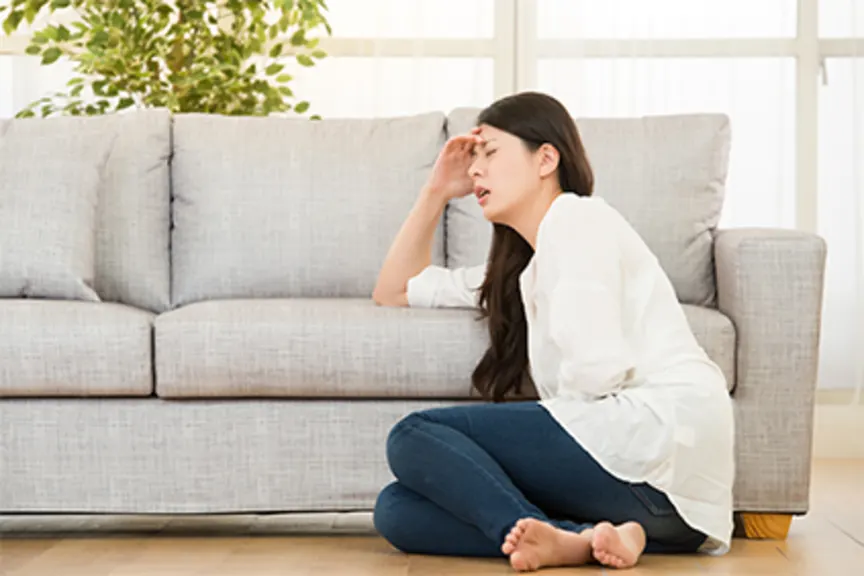 有胃痛的妇女坐在地板上在家。