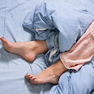 Woman with restless leg syndrome in bed.