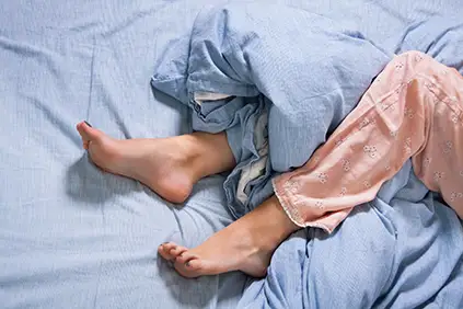 有不安分的腿综合症的妇女在床上。