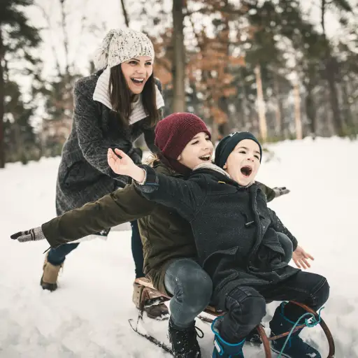 Mother sledding with sons during winter