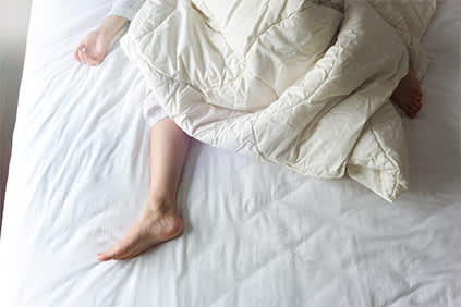 女人的胳膊和腿在被子里躺在床上。