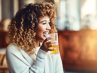 女人边喝啤酒边笑。