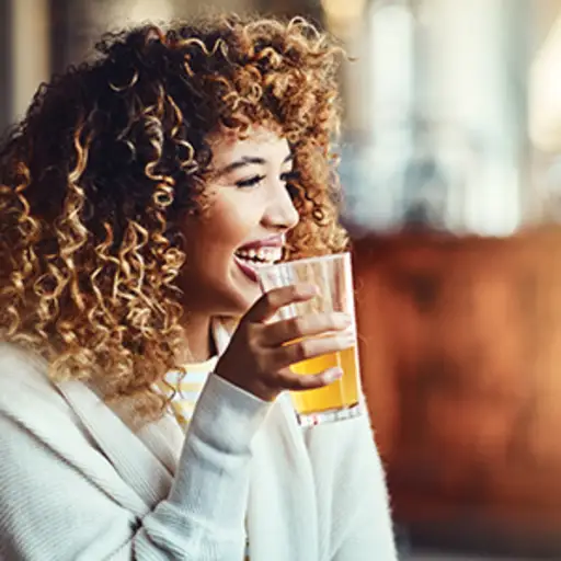 一个女人一边喝啤酒一边笑。