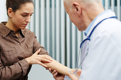 一位年轻的女士给她的医生看她手臂上的皮肤。