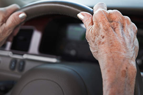 在资深女人的方向盘上的手老年斑。