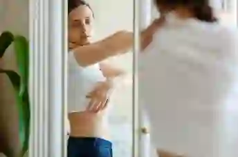 一个女人在镜子里看着她腹部的皮疹