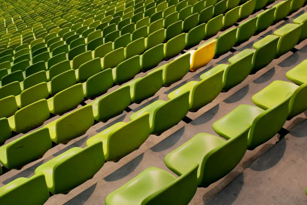体育场充满绿色的椅子，一把椅子是黄色的