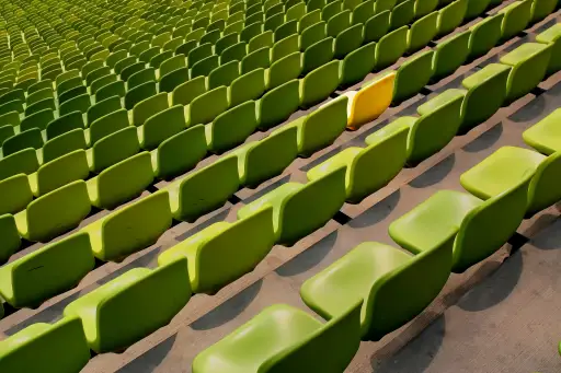 体育场里到处都是绿色的椅子，其中一把椅子是黄色的