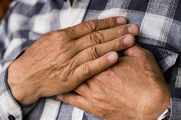 心脏跳动快,双手放在胸前的老人。