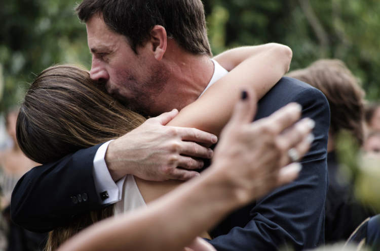 父亲抱着十几岁的女儿，亲吻她的前额