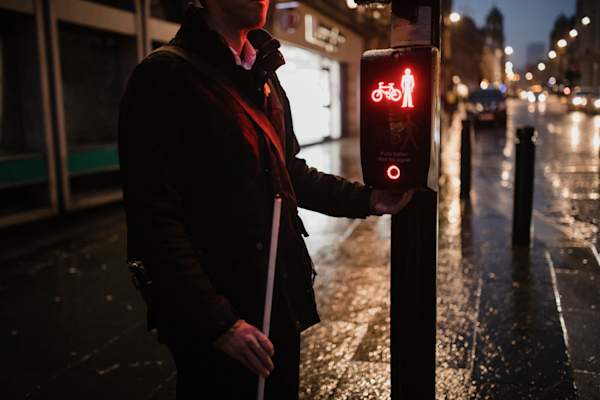 在十字路口拄拐杖的视障人士