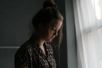sad woman standing near window