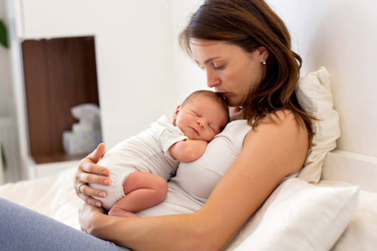 母亲抱着新生儿坐在床上。