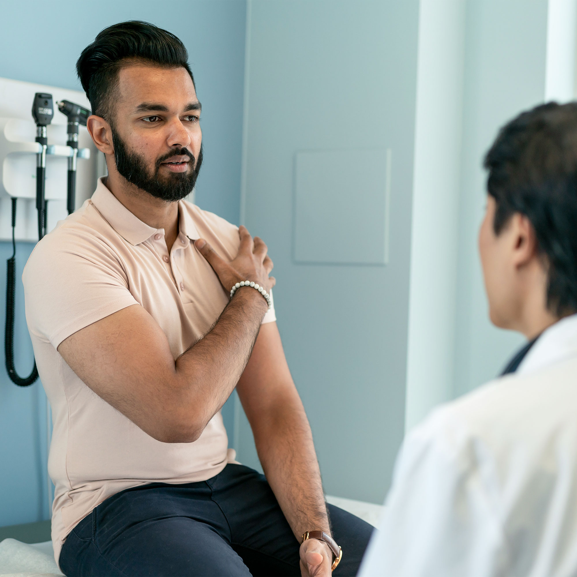 一个男人和他的医生谈论肩膀疼痛