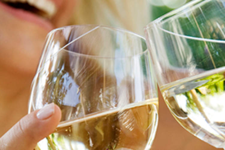 女人喝白葡萄酒与朋友的图像。
