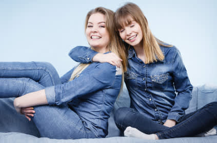 两个女人穿着蓝色的衣服，微笑着拥抱着。