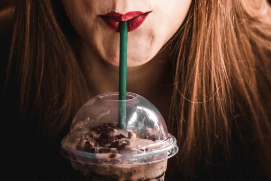 穿红色唇膏的妇女饮用的frappuccino